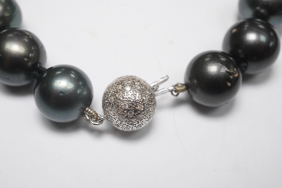 A modern single strand Tahitian black pearl necklace, with diamond cluster set 14k white metal spherical clasp, 40cm. Condition - fair to good